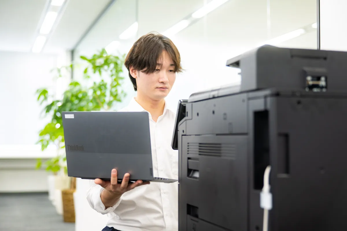 ノートPCを片手にコピー機の対応をするCEメンバー
